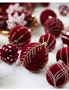 Macro shot of deep red velvet Christmas ball with intricate gold glitter leaf patterns