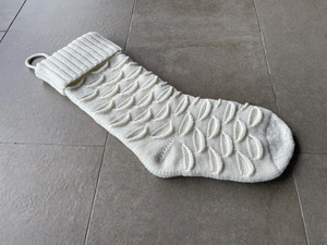 Detail of white knitted Christmas stocking with decorative fish scale textured pattern