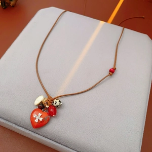 Detail of red heart pendant with silver cross on bohemian beaded wax cord necklace
