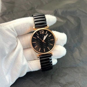 Macro shot of rose gold watch case with textured black dial and glossy link strap