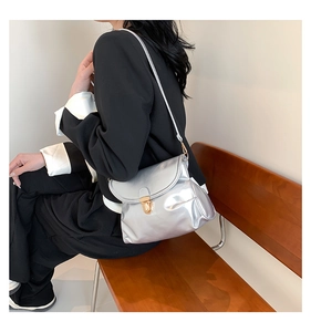 Detail of silver metallic mirror finish bag with golden buckle on a wooden bench