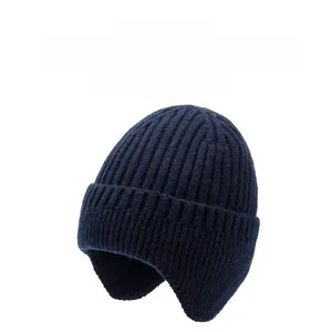 Close-up of thick ribbed knit texture and metallic button detail on a navy winter earflap hat