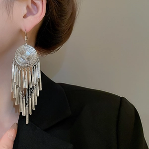 Detail of long silver tassel earrings with layered metal pendants on a model
