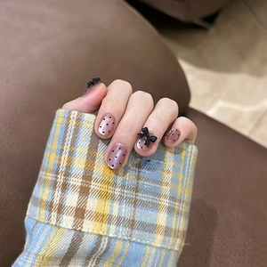 Handmade nude pink short press-on nails with black polka dots and 3D bow accents