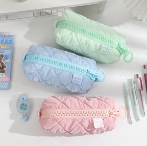 Quilted macaron pencil cases in mint, blue, and pink with chunky zipper on desk