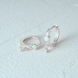 Close-up of S925 silver hoop earrings with white opal and sparkling cubic zirconia stones