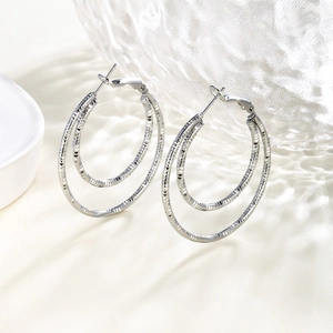 Detail of silver double circle earrings with textured diamond-cut chain pattern