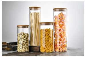 Detailed view of four glass storage jars in different sizes with wooden airtight lids