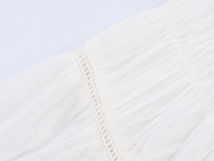 Detailed close-up of white poplin shirt featuring intricate pleats and lace trim details