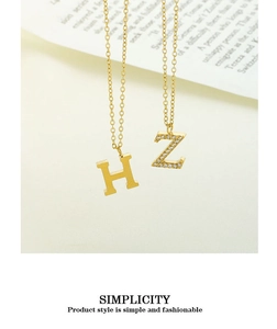 Close-up of golden alphabet necklaces featuring polished letter H and zircon-studded Z