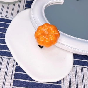 Close-up of bright orange pumpkin-shaped hair clip with a sturdy black duckbill clip
