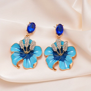 Dettaglio macro di orecchini a fiore tropicale con petali blu e cristalli lucenti