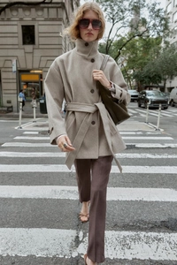 Detail of light camel wool coat featuring a stand collar and elegant waist tie belt