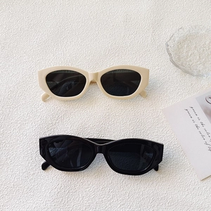 Close-up of stylish cat-eye sunglasses in black and cream on a textured white background