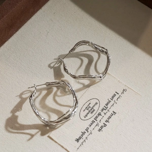 Minimalist silver wave hoop earrings featuring irregular twisted geometric liquid metal design