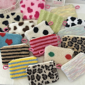 Flat lay of assorted plush coin purses in leopard, heart, and cow patterns with pink zippers