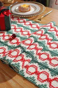 Close-up of cotton Christmas table runner with red green tassels and geometric patterns
