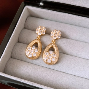 Macro shot of vintage gold drop earrings with intricate crystal floral details