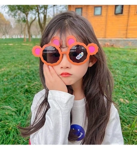 Close-up of cute orange bear ear sunglasses on a young girl model
