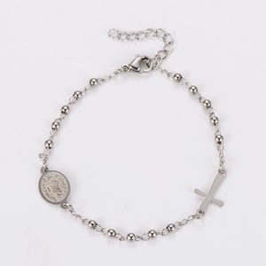 Close-up of silver beaded chain bracelet featuring religious cross and St. Benedict charms