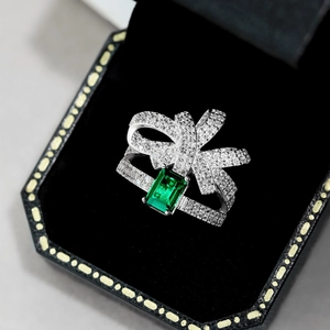 Macro detail of S925 silver bow ring with emerald green zircon in black velvet box