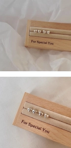 Close-up of minimalist s925 silver heart stud earrings on a wooden display stand