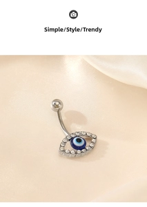 Macro shot of silver evil eye belly ring with sparkling zircon inlays on silk fabric