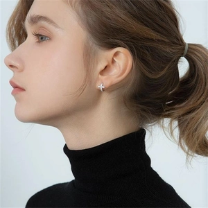 Detail of silver S925 sterling silver hoop earrings with crosses worn by a model