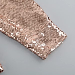 Close-up of rose gold sequin fabric showing detailed craftsmanship on a luxury dress set
