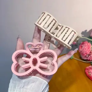 Matte pink bow and beige geometric hair claws in hand for stylish updo styling