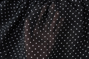 Dettaglio del tessuto in chiffon nero trasparente a pois bianchi con trama traspirante