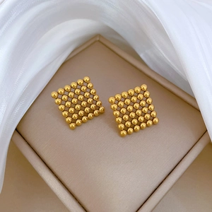 Minimalist square beaded titanium steel earrings in gold finish on jewelry display