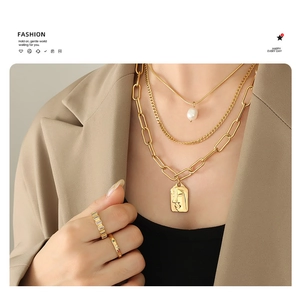 Detail of layered gold chains with freshwater pearl and vintage embossed coin pendant
