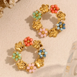 Detail von 18K vergoldeten Blumenohrringen mit bunten Perlen auf beigem Grund