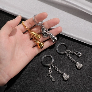 Creative stainless steel boxing glove and lucky bag keychains on black textured background