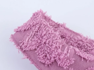 Detailed close-up of pink textured fabric with soft plush fringe and quality stitching