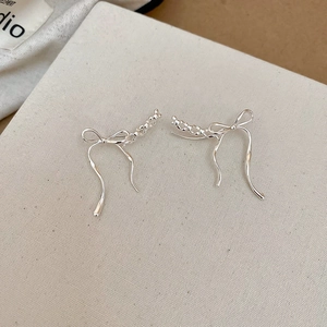 Detail of silver bow earrings with ribbon tassels and sparkling crystal accents