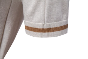 Dettaglio della manica avorio della polo in maglia con riga marrone e bordo a costine