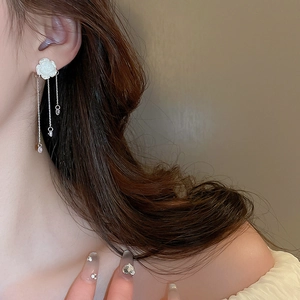 Détails de boucles d'oreilles camélia avec glands en cristal portées par un mannequin