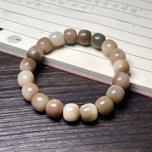 Macro shot of gradient Bodhi seed bead bracelet with cat paw carving on wooden desk
