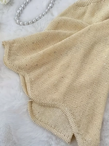 Detail van champagne goudgebreide stof met pailletten op een witte achtergrond van imitatiebont