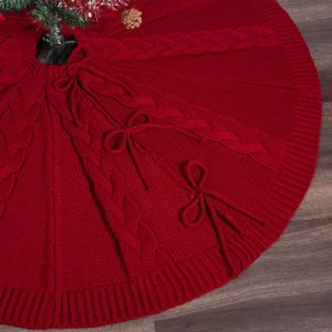 Close-up of red knitted Christmas tree skirt with classic cable patterns and tie closures