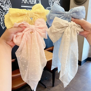 Detail of four colorful oversized bow hair clips with soft polka dot texture and ribbons