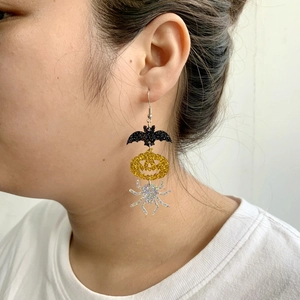 Cute Halloween acrylic earrings featuring glitter bat, pumpkin, and spider charms on model