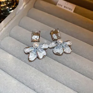 Elegant flower stud earrings with artificial pearls and crystals on gray velvet tray