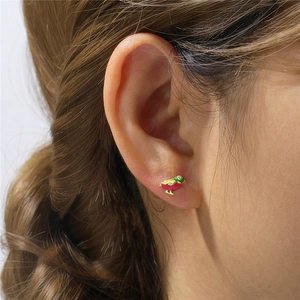 Close-up of a bird stud earring with colorful enamel and a sparkling diamond on the model