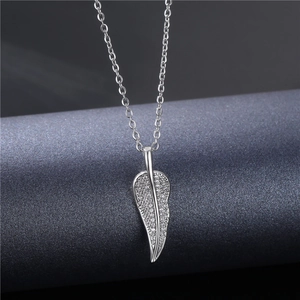 Silver micro-pave zircon leaf pendant necklace with thin chain on a textured background