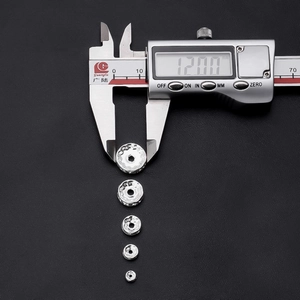 Macro view measuring a 12mm silver wavy metal spacer bead with a digital caliper