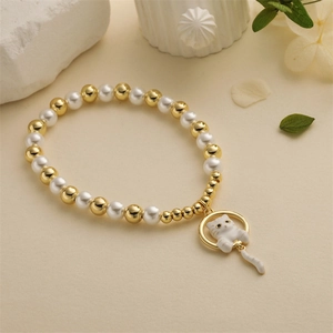 Détail du bracelet avec perles dorées, perles blanches et pendentif chat mignon