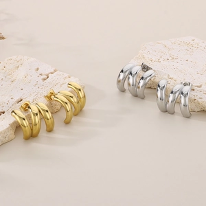 Macro detail of gold and silver triple-layered C-shaped minimalist hoop earrings